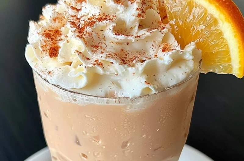 Cozy orange cinnamon milk tea in a cup with a cinnamon stick garnish.