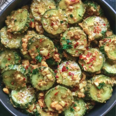 Cucumber salad topped with peanut dressing in a vibrant bowl