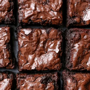 Delicious fudgiest brownies topped with chocolate drizzle on a wooden table