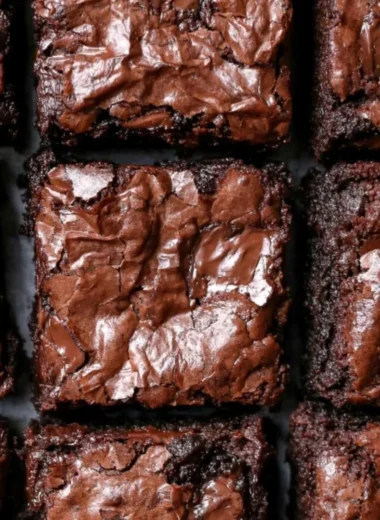 Delicious fudgiest brownies topped with chocolate drizzle on a wooden table