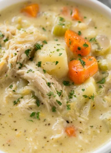 Bowl of healthy chicken pot pie soup with vegetables and herbs