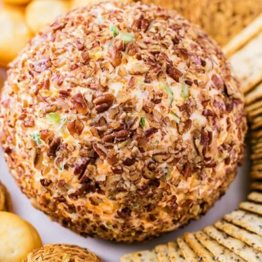 Delicious holiday cheese ball served with crackers and garnished with herbs.