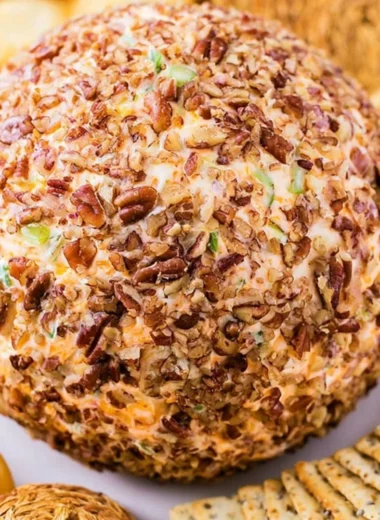 Delicious holiday cheese ball served with crackers and garnished with herbs.